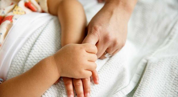 infant holding mother's hand